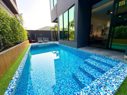 a large blue swimming pool next to a building at Huge Luxury, 3 Bedroom, private pool villa near to the beach - Jomtien - LV99 in Jomtien Beach