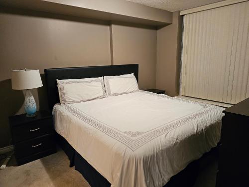 a bedroom with a bed with white sheets and a window at King Luxury Ensuite Private Room in Toronto