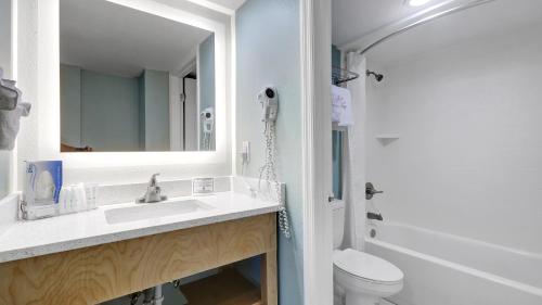 a bathroom with a sink and a toilet and a mirror at Boardwalk Inn and Suites in Daytona Beach