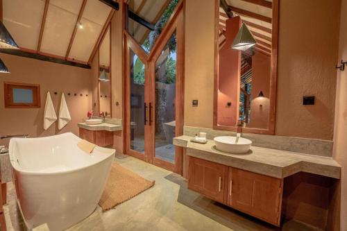 a bathroom with a tub and a sink and a mirror at Nisala Villas in Hikkaduwa