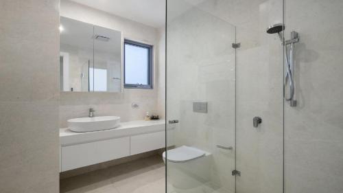 ein weißes Badezimmer mit Waschbecken und Dusche in der Unterkunft Sea Breeze Accom Holidays in Copacabana