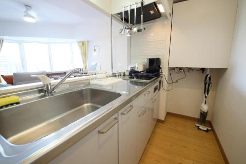 a kitchen with a stainless steel sink and white cabinets at AMS TOWER 806 in Sapporo