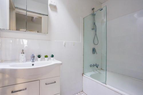 y baño blanco con lavabo y ducha. en Superb 2 Bedroom House Darlinghurst 2 E-Bikes Included en Sídney