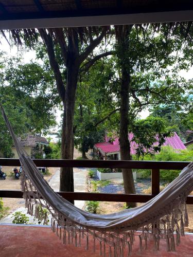 a hammock hanging from a porch with trees at Ocean Vibes in Thongsala