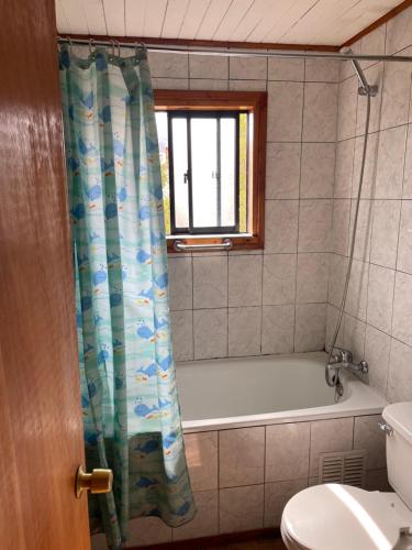 a bathroom with a bath tub and a shower curtain at Casa en Choshuenco a 180 metros de la Playa, Panguipulli, Los Ríos in Panguipulli