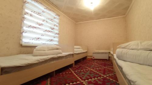 een kleine kamer met twee bedden en een raam bij Happy Hostel in Tamga in Tamga