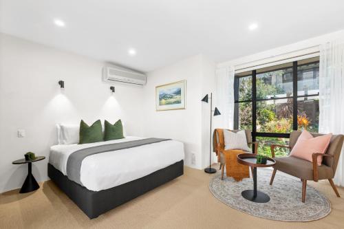 a white bedroom with a bed and a chair at Balmain Retreat - 2BR + Study in Sydney