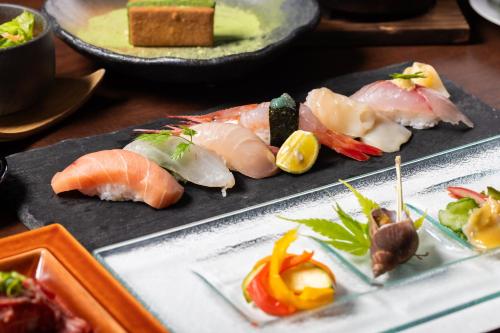 um monte de sushi em pratos numa mesa em Hotarutei Villas em Yamanouchi