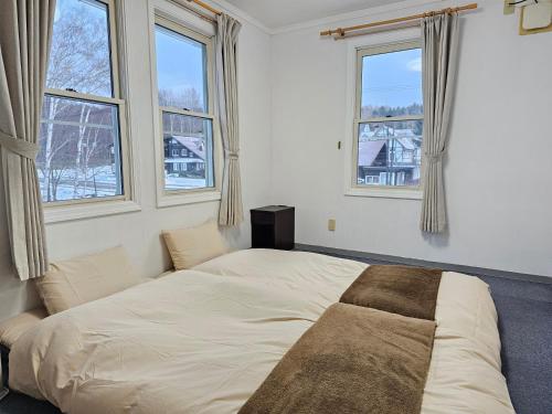 Ce lit se trouve dans un dortoir doté de 3 fenêtres. dans l'établissement White House ホワイト ハウス, à Shimukappu