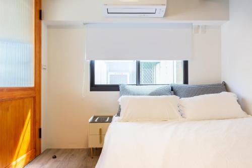 a bedroom with a bed with white sheets and a window at Nan Yi Style in Tainan