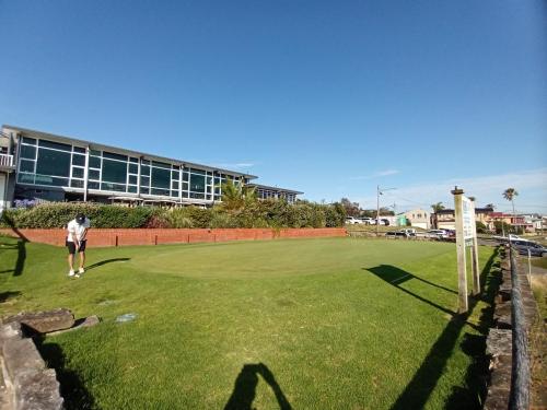 a man standing on a green field with a building in the background at Brand NEW VIP Luxury 5/5 Star Beachside Escape in Sydney