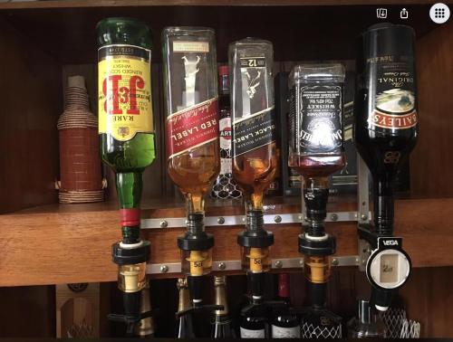 a row of wine bottles and glasses on a shelf at Iarimbato Hotel in Antananarivo
