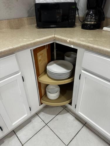 a cabinet with plates and a microwave in a kitchen at Traveler Stay PLUS in Eagle Pass