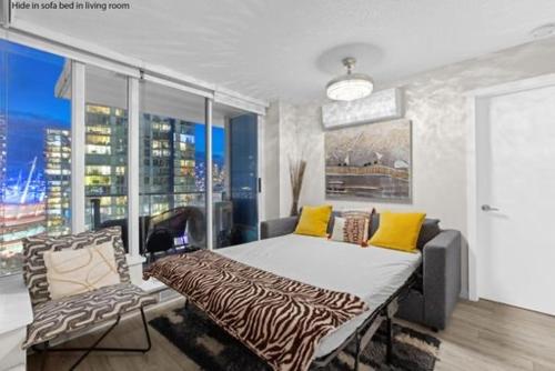 a bedroom with a bed and a couch and a window at Beautiful Bright Modern Condo with Water view and AC in DT Vancouver 2BR,3BD,2BT sleeps 6 guests Free parking Netflix Included in Vancouver