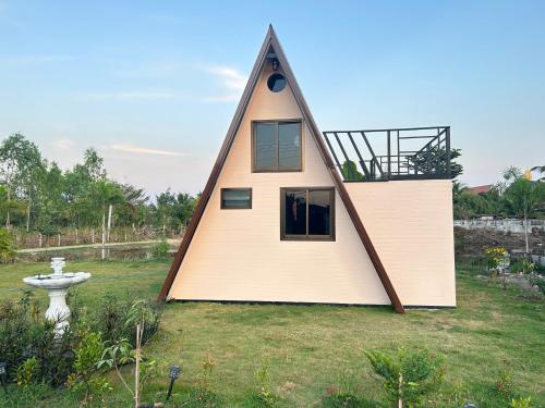 une petite maison avec un toit triangulaire sur une cour dans l'établissement บ้านริมน้ำ สำหรับครอบครัว, à Buriram