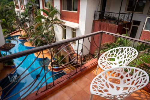 a balcony with two chairs and a swimming pool at Ronne's Candy Floss Blue Lagoon villa in Guirim