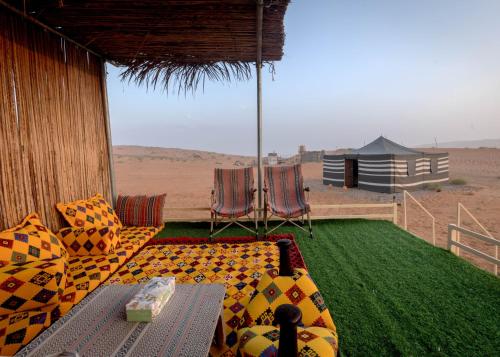 a patio with a couch and chairs in the desert at SAFARI-Glamping in Al Wāşil