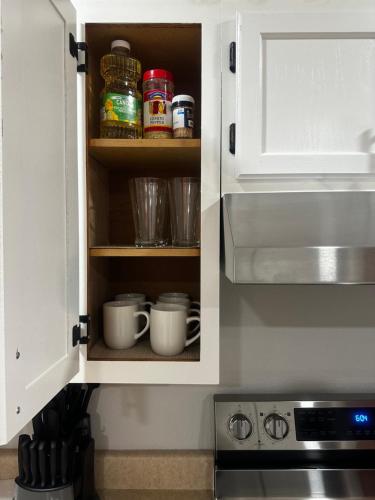a kitchen cabinet with cups in it next to a stove at Traveler Stay PLUS in Eagle Pass