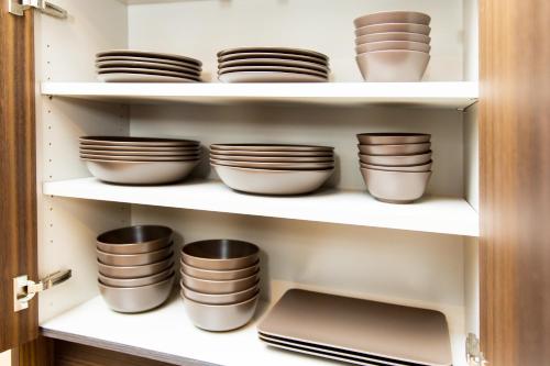 a cupboard filled with plates and bowls at Cairns House by SANA in Tateyama