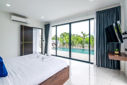 a bedroom with a large bed and a swimming pool at Mango Hill Residence in Rawai Beach