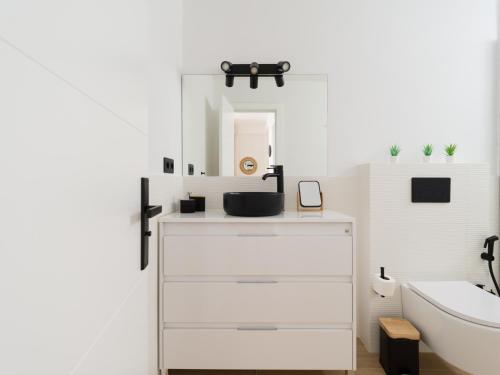 La salle de bains blanche est pourvue d'un lavabo et d'un miroir. dans l'établissement Pascal Home By CanariasGetaway, à Las Palmas de Gran Canaria