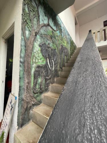 a mural on the wall of a building with stairs at Cocoplant Surf Inn in Midigama