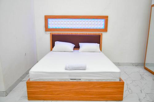 Schlafzimmer mit einem Bett mit einem Holzrahmen und einem Fenster in der Unterkunft Jonna Pluto Highland By ZIRI in Cihideung