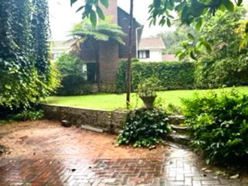 a garden with a brick path in front of a house at Sherwood Garden Cottage in Durban