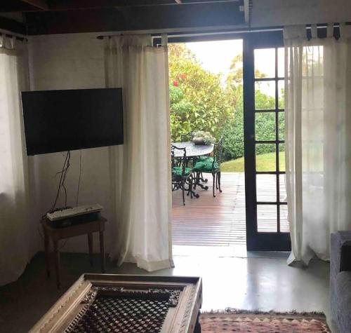 a living room with a screened in porch with a table at Sherwood Garden Cottage in Durban