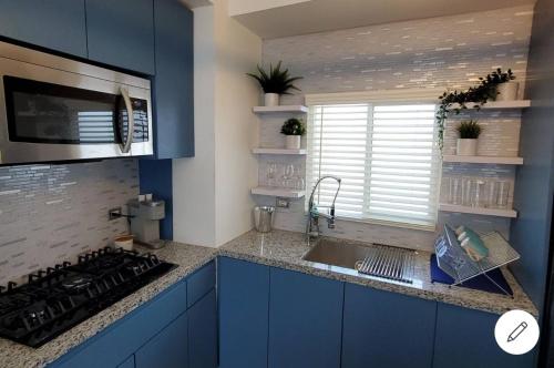 Oceano 21 في تيخوانا: مطبخ مع دواليب زرقاء ومغسلة ونافذة