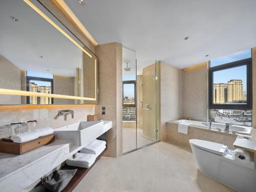 ein Badezimmer mit zwei Waschbecken, einer Badewanne und einer Dusche in der Unterkunft Hilton Garden Inn Heze in Heze