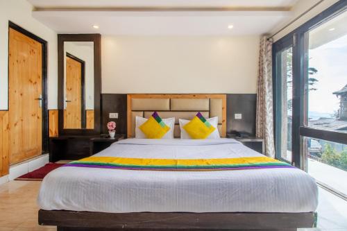 a bedroom with a large bed and a large window at Itsy Hotels Avantika With Forest View in Shimla