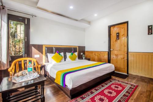 a bedroom with a king sized bed and a table at Itsy Hotels Avantika With Forest View in Shimla