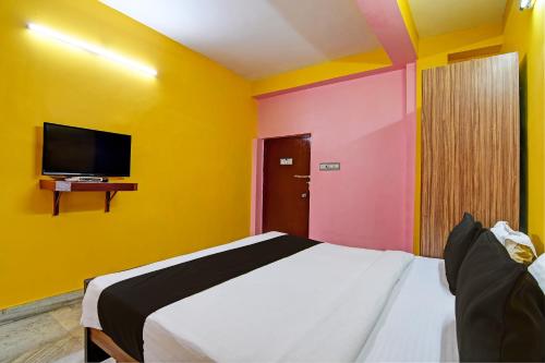 a bedroom with yellow and pink walls and a bed at Flagship Hotel Red Rose Near Noapara Metro Station in Kolkata