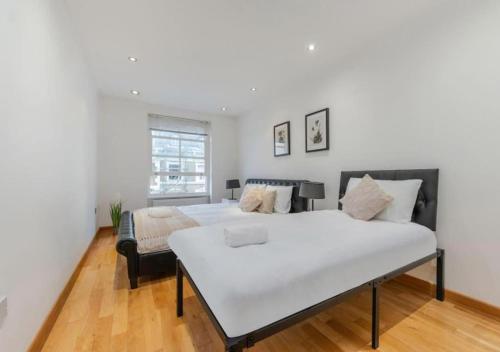 a white bedroom with a bed and a chair at Kensington & Chelsea - Stylish Apartment in Central London in London