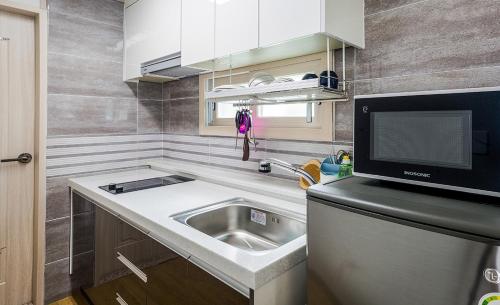 a small kitchen with a sink and a microwave at Donnaeko Pension in Seogwipo