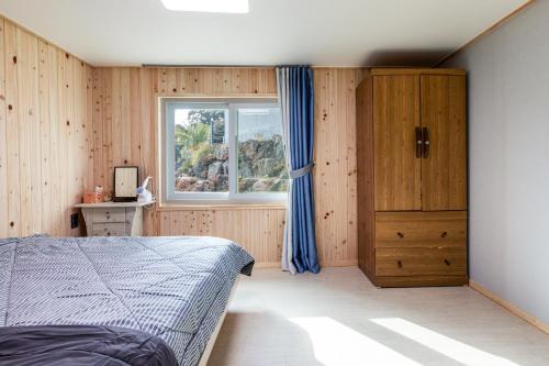 a bedroom with a bed and a window at Donnaeko Pension in Seogwipo