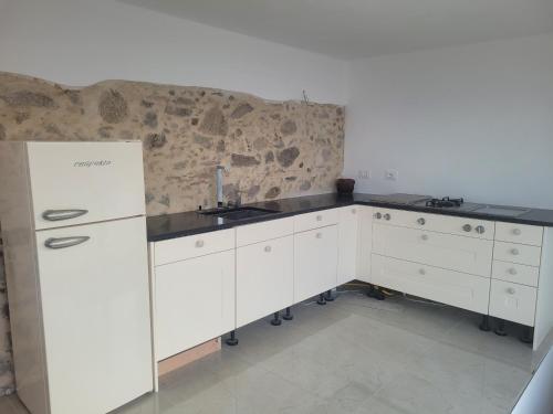 La cuisine blanche est équipée d'un évier et d'un réfrigérateur. dans l'établissement Casa Mare * Monte * Mille Stelle, à Santa Caterina dello Ionio