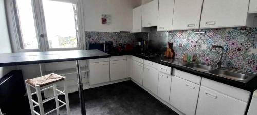 a small kitchen with white cabinets and a sink at Armorino - Appartement Charmant 2 Chambres - Proximité de tout in Lannion