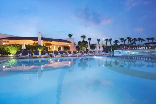 ein großer Pool mit Stühlen und ein Gebäude in der Unterkunft Aydinbey King's Palace & Spa in Side