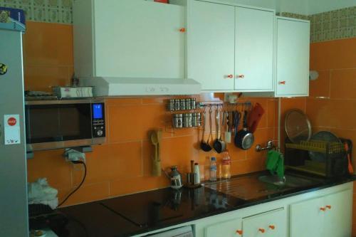 a kitchen with white cabinets and an orange tiled wall at Apartamento en Tetuán in Tetouan