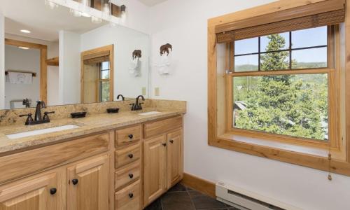 La salle de bains est pourvue de 2 lavabos et d'une fenêtre. dans l'établissement Powder Ridge Cabin Rosebud 7, à Big Sky
