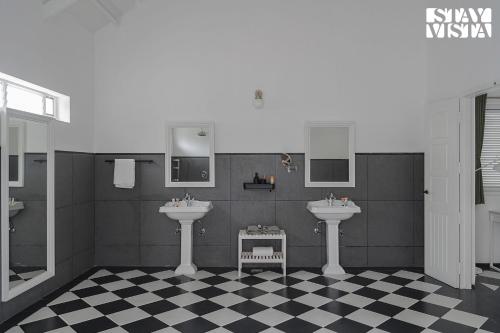 a bathroom with two sinks and a checkered floor at The Mudra Manor 4BR Coorg temperature controlled pool Villa in Madikeri