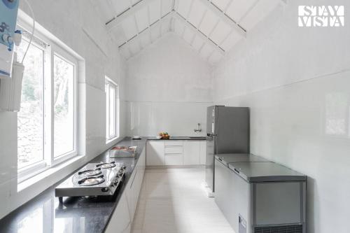 a white kitchen with a refrigerator and a sink at The Mudra Manor 4BR Coorg temperature controlled pool Villa in Madikeri