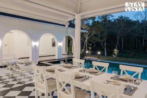 a dining room with a table and chairs on a checkered floor at The Mudra Manor 4BR Coorg temperature controlled pool Villa in Madikeri