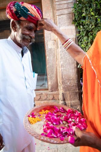 a man wearing a turban holding a tray of flowers at Kot Dunara - A 16th Century Castle near Jodhpur in Jodhpur