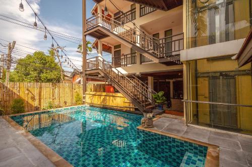 a swimming pool in front of a building with a staircase at THEE Kashatharn by TH District in Chiang Mai