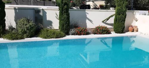 a blue swimming pool with plants and a white fence at The Central Residence - Kassiopi Corfu Villas in Kassiopi