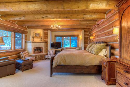 Dormitorio en cabaña de madera con cama y chimenea en MV Leaf Lodge, en Big Sky