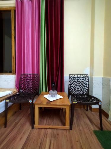 two chairs and a table in a room at Orange sky home stay gadaGushaini near jibhi in Jibhi